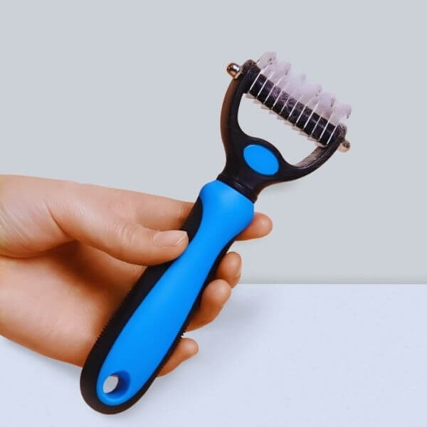 Hand showing size and grip of the Pet Store ED grooming tool.
