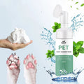 Pet foot cleansing foam bottle with foam in hand, clean and dirty dog paws, mint leaves, and water.