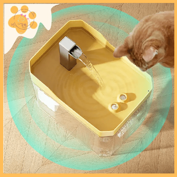 Orange cat drinks from yellow interactive pet water fountain on wooden floor