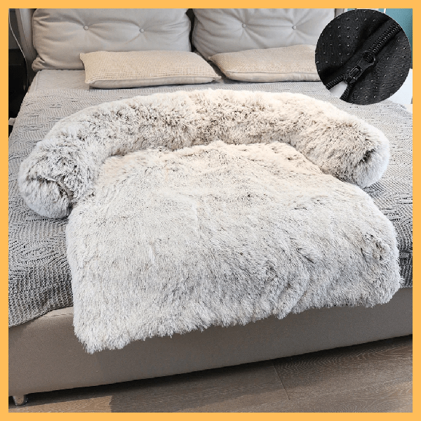 Comfy Shield plush pet blanket in light gray on a bed, featuring anti-slip bottom detail.