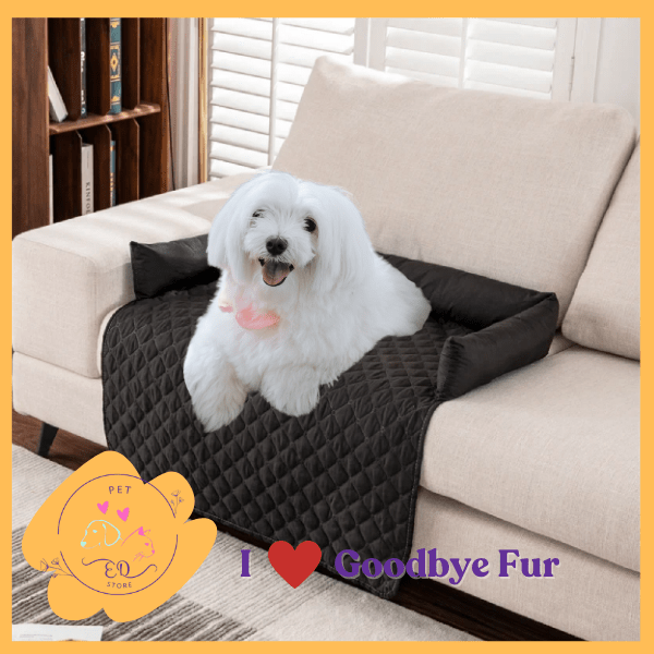 White dog on a black quilted pet sofa protector, Goodbye Fur brand, cozy living room.
