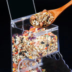 Clear plastic seed dispenser full of mixed bird seed, wooden spoon scooping seeds