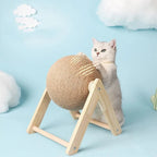 Gray cat playing with sisal rope scratching ball on wooden stand, blue cloud background