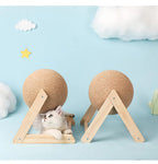 Cat lying under wooden and sisal scratching ball with playful cloud decor background