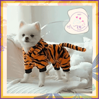 Small white dog wearing a tiger-striped hoodie costume on a white sofa, pet store logo visible