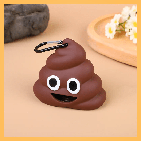Poop emoji dog poop bag dispenser with carabiner on beige surface, flowers in background