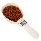 Digital pet food scoop with kibble and LCD weight display on white background