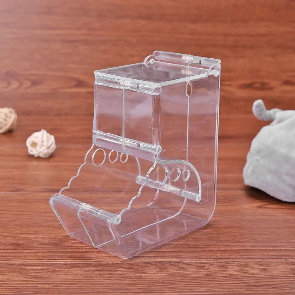 Clear acrylic hamster food dispenser on wood surface, small animal cage accessory