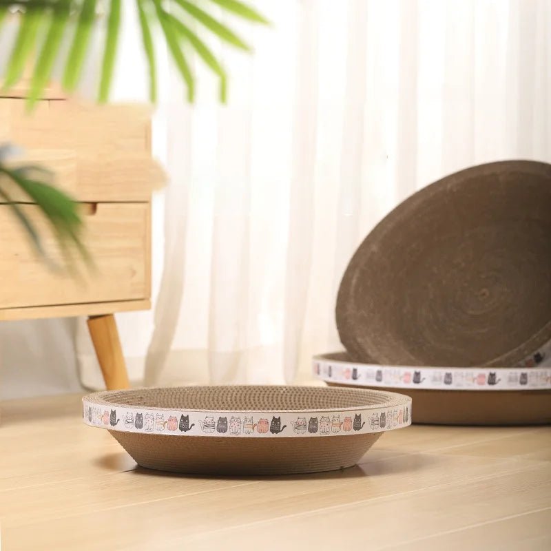 Round cardboard cat scratcher bed with cat pattern trim on light wood floor indoors