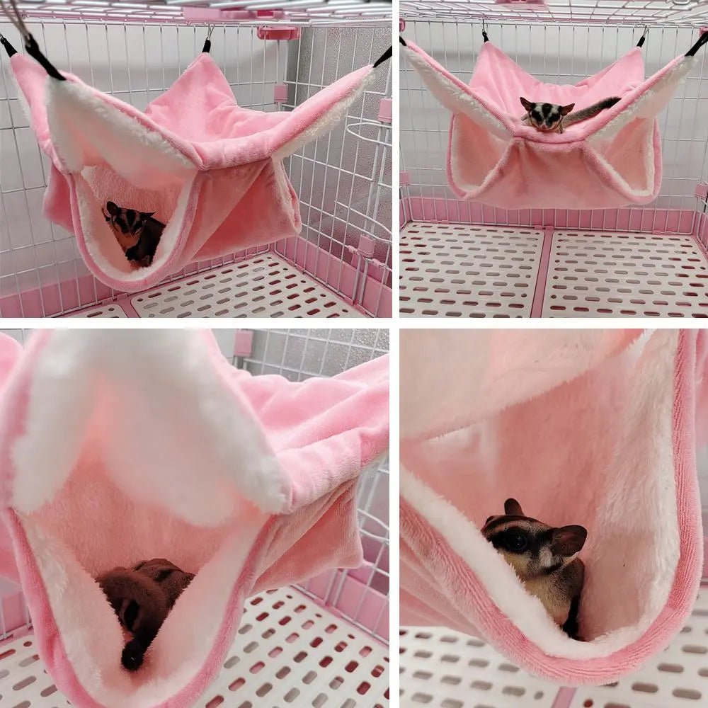 Sugar glider resting in a pink fleece hammock inside a small animal cage