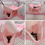 Sugar glider resting in a pink fleece hammock inside a small animal cage