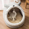 White cat lying inside a plush animal-shaped cat bed with hanging toy on wooden floor