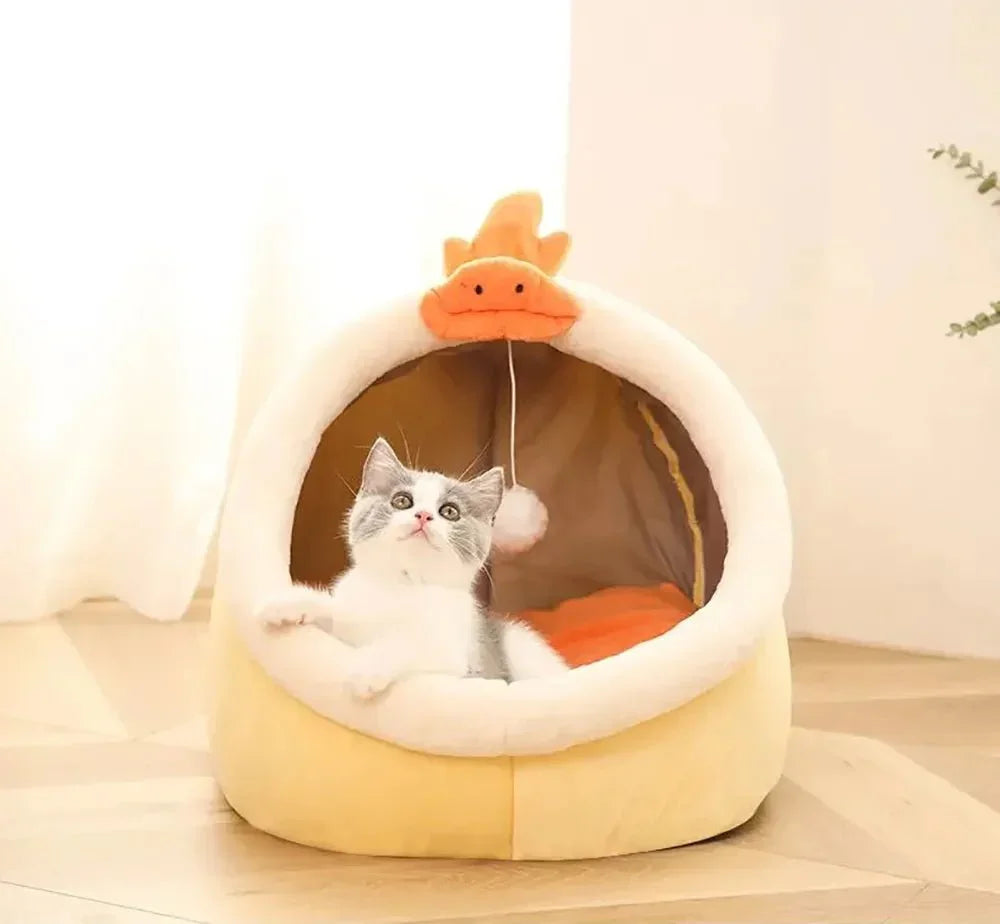 Gray and white kitten in a cozy yellow duck-shaped cat bed on wooden floor