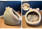 Plush cat bed with bunny ears and tail, fluffy cat inside, cozy pet furniture on wood floor