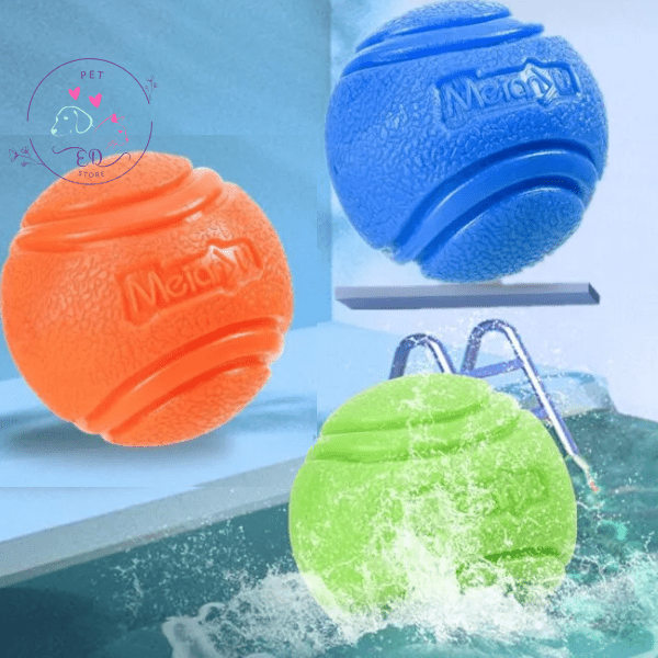 Three textured dog chew balls in blue, orange, and green near a swimming pool.