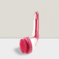 Pink pet bath brush with silicone bristles on a clear handle, displayed on a white surface.