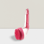 Pink pet bath brush with silicone bristles on a clear handle, displayed on a white surface.