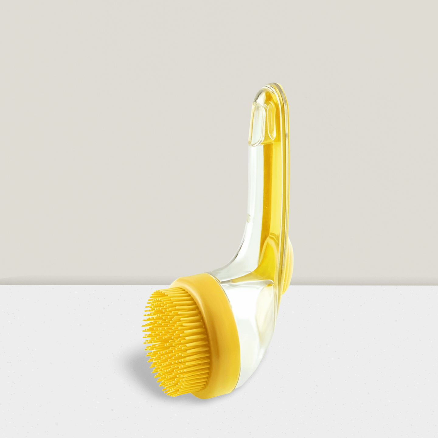 Yellow pet bath brush with silicone bristles and clear handle on a neutral background