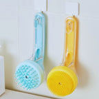 Blue and yellow pet bath brushes with soft bristles hanging on hooks in a bathroom