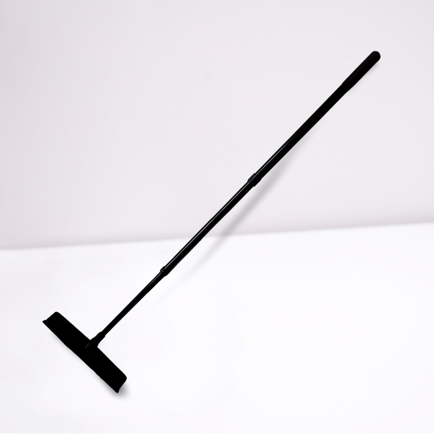 Black silicone broom cleaning tool with long handle on white background