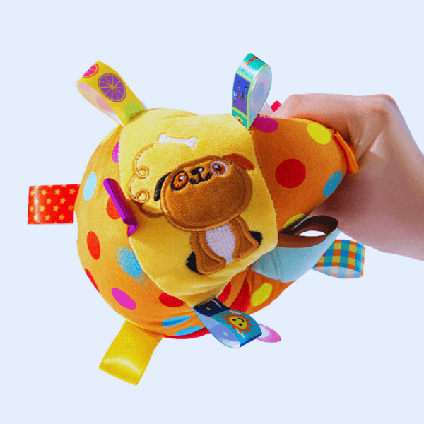 Hand holding colorful polka dot dog squeaky plush toy with ribbons for pets