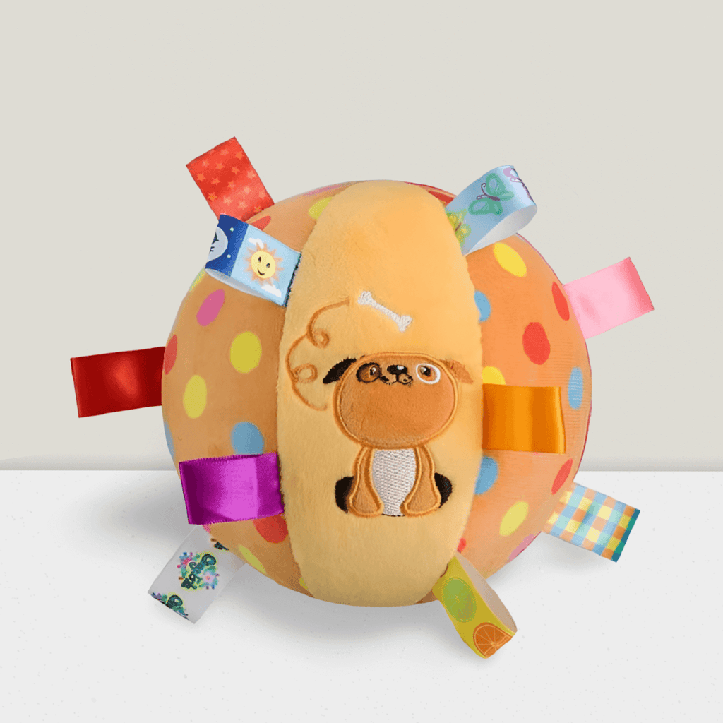 Colorful spotted plush dog toy ball with puppy embroidery and ribbon tags on white surface