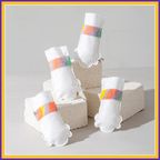 Four white Drypaws dog shoes with colorful bands displayed on light blocks