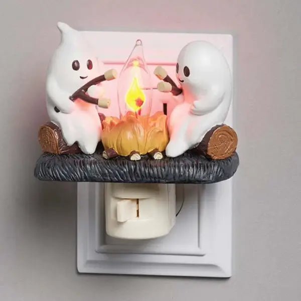 Ghost campfire night light with two resin ghosts roasting marshmallows over a glowing orange fire, on a plain background
