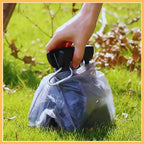 Hand using compact grip scooper with waste bag on grass outdoors
