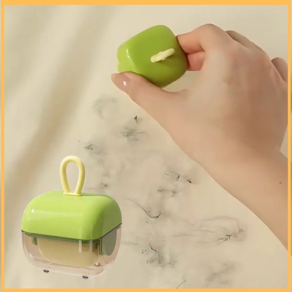 Hand using portable green Haarrol hair remover on fabric with visible hair
