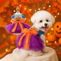 Bichon Frisé wearing the halloween dress for dogs next to the same dress displayed on a mannequin, with pumpkin and autumn decor in the background