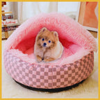 Small fluffy dog sitting in a pink plush pet bed with checkered sides indoors