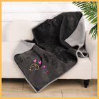 Reversible waterproof black and gray dog blanket draped on a white sofa