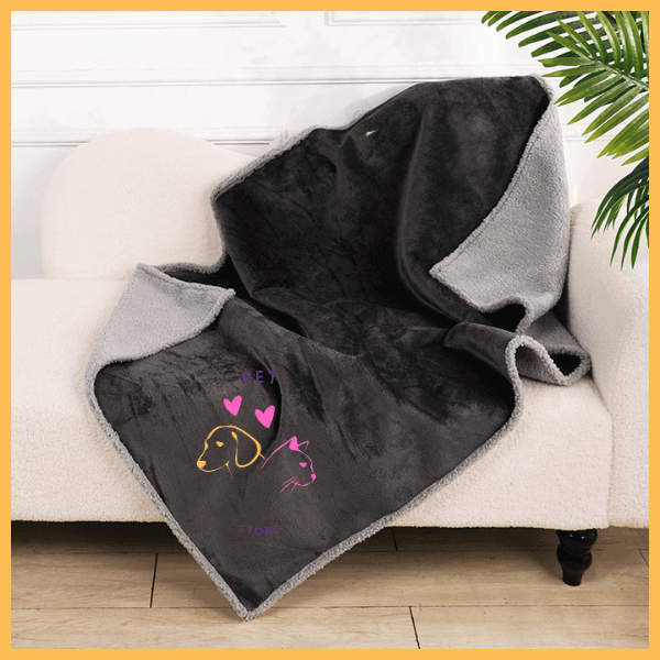 Reversible waterproof black and gray dog blanket draped on a white sofa