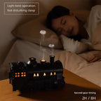 Train diffuser on a bedside table with a sleeping woman in the background, showing the 2 or 8 hour timer setting