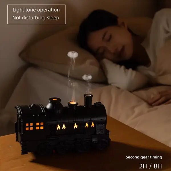 Train diffuser on a bedside table with a sleeping woman in the background, showing the 2 or 8 hour timer setting