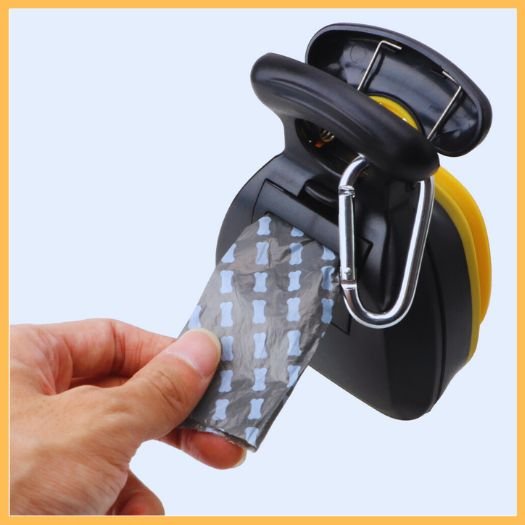 Hand pulling waste bag from dog poop scooper with dispenser and carabiner