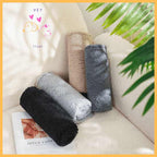 Four rolled sherpa dog blankets in beige, gray, and black on a cream sofa