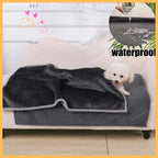 Small white dog on sofa with dark gray waterproof sherpa dog blanket, living room setting