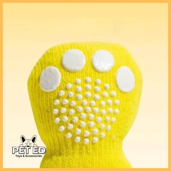 Yellow non-slip grip dog sock with white paw print on sole, pet accessory product photo.
